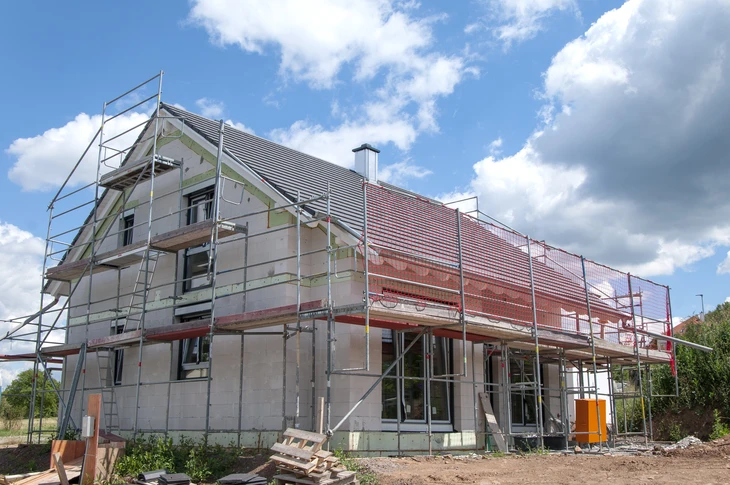 Chantier de construction résidentielle en cours avec maison individuelle à étage partiellement achevée